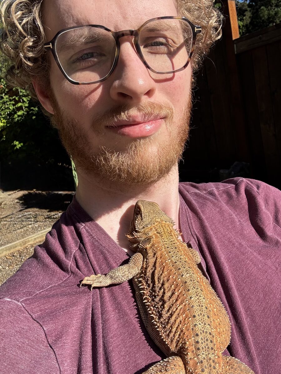 Nathan in full sun with a bearded dragon resting on his chest